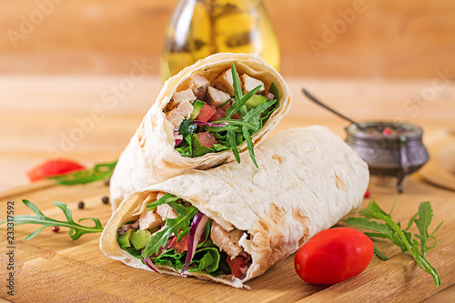 Tortillas wraps with chicken and vegetables on wooden background. Chicken burrito. Healthy food.