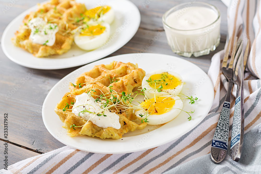 Healthy breakfast or snack. Potato waffles and boiled egg on grey wooden table.