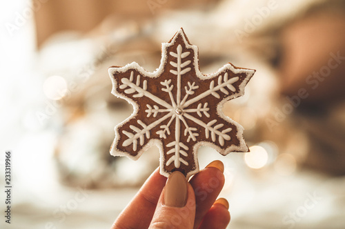 Female hands holding cookie shaped snowflake. Christmas mood. Concept of winter greeting. 