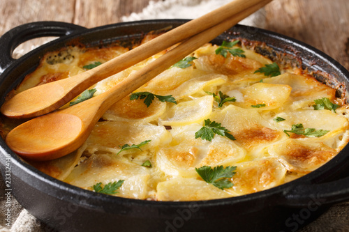 Finnish Janssonin Kiusaus hot baked potatoes with anchovies, onions and heavy cream close-up in a frying pan. horizontal photo