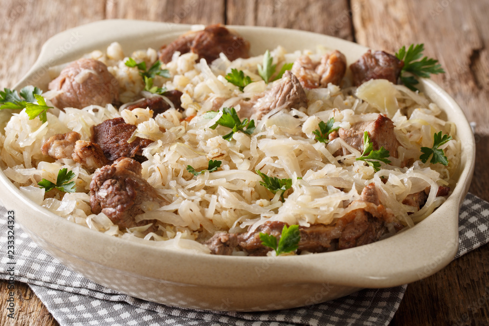 Mulgikapsas Estonian food slow-cooked pork with sauerkraut, onions and barley closeup in a dish. horizontal