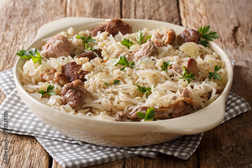 Estonian main course Mulgikapsas cooked pork with sauerkraut, onions and barley closeup in a dish. horizontal