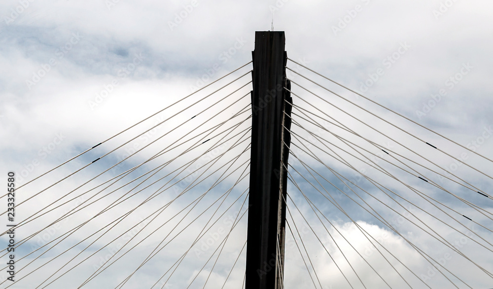 Fototapeta premium Steel cables of a bridge surrounded by clouds