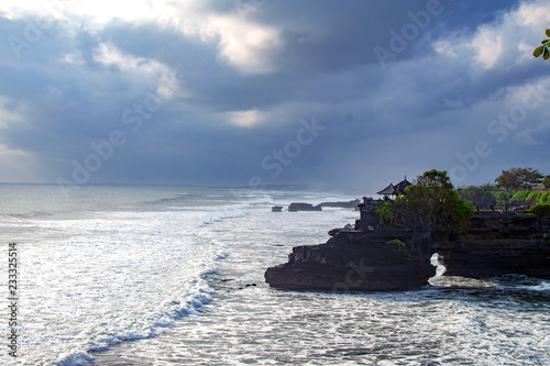 Chimeric temple on the water. Water temple in Bali. Indonesia nature landscape. Famous Bali landmark. Splashing waves and stone. Cloudy day in Indonesia. Water and rocks before storm photo