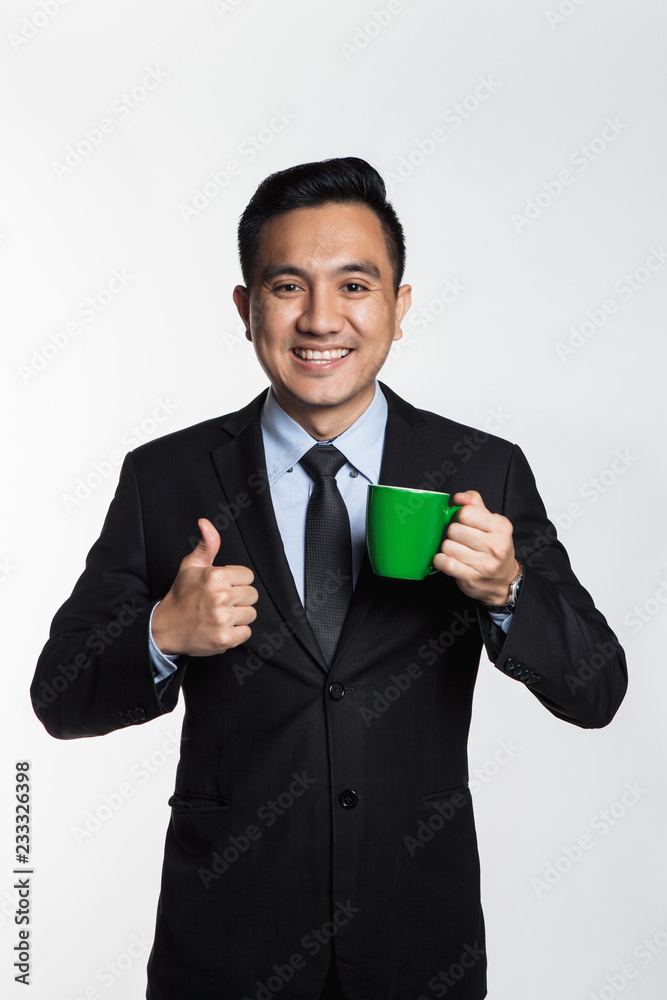 Man in suit holding a mug with thumbs up Man in suit holding a mug with thumbs up