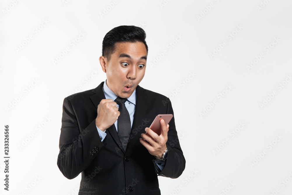 Man in suit with surprise expression while looking at his phone Man in suit with surprise expression while looking at his phone