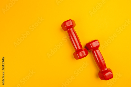 Fitness dumbbells on bright yellow background. Fitness concept © NewFabrika