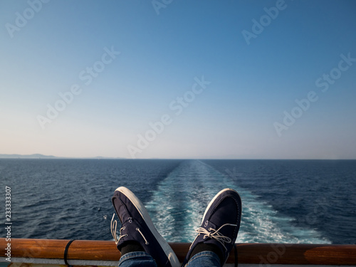Man holding legs on cruise boat fence