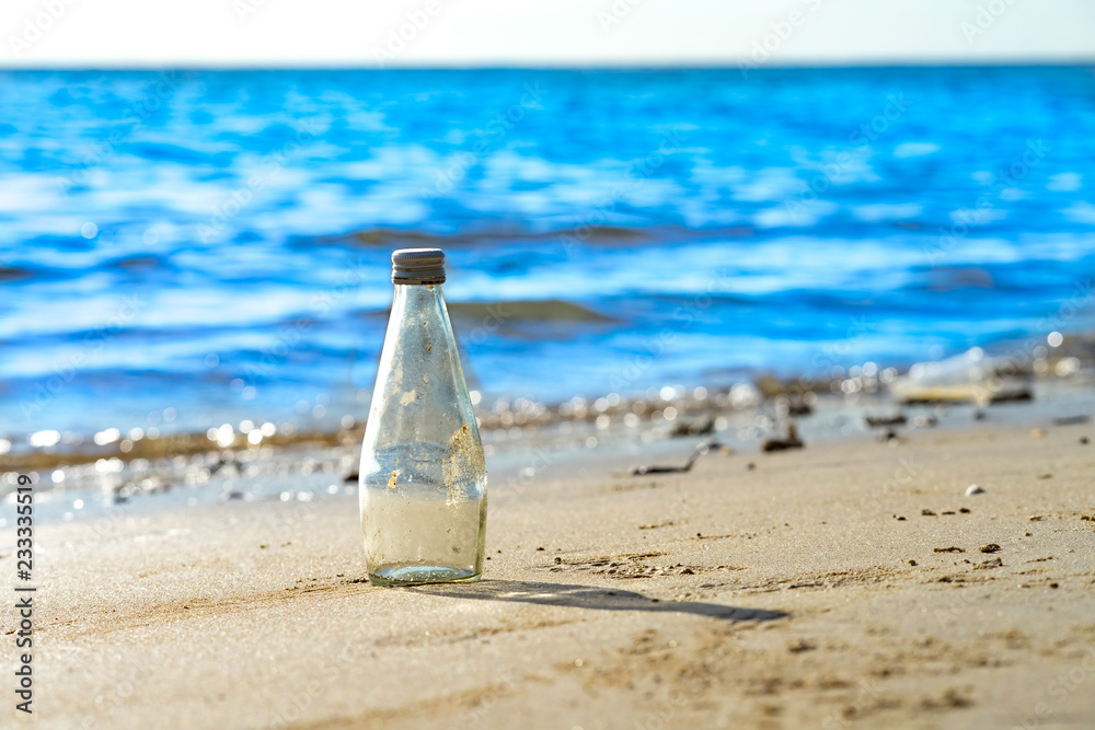 white clear glass bottle with lid and shadow on sand sea beach white clear glass bottle with lid and shadow on sand sea beach