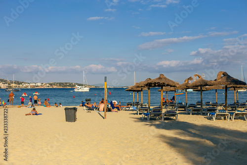 Sunny sandy beach with umbrellas and deck chairs on a blue sky  background