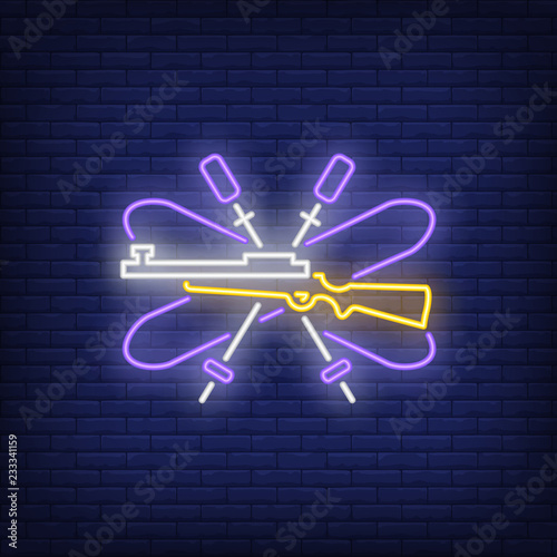 Purple biathlon equipment neon sign. Glowing ski, ski poles and gun on dark blue brick background. Can be used for sport, Olympic games, winter games