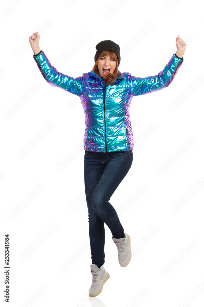 Cheering Young Woman In Vibrant Down Jacket And Cap Cheering Young Woman In Vibrant Down Jacket And Cap