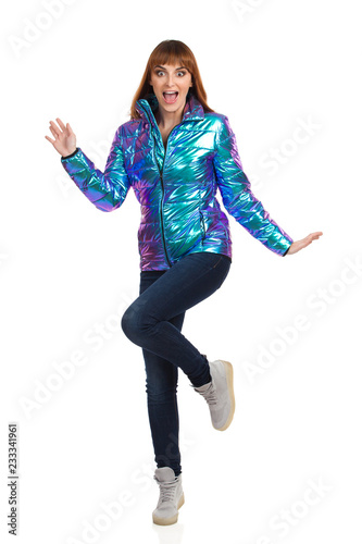 Young Woman In Vibrant Down Jacket Is Shouting And Standing On One Leg