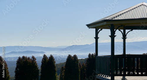 A pergola high above a valley with mountain sin the distance and pine trees in the foreground. photo