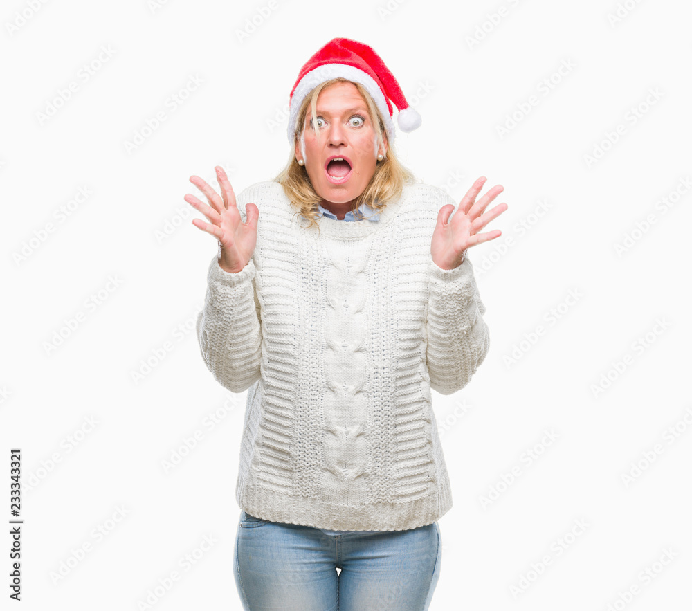 Middle age blonde woman wearing christmas hat over isolated background crazy and mad shouting and yelling with aggressive expression and arms raised. Frustration concept. Middle age blonde woman wearing christmas hat over isolated background crazy and mad shouting and yelling with aggressive expression and arms raised. Frustration concept.