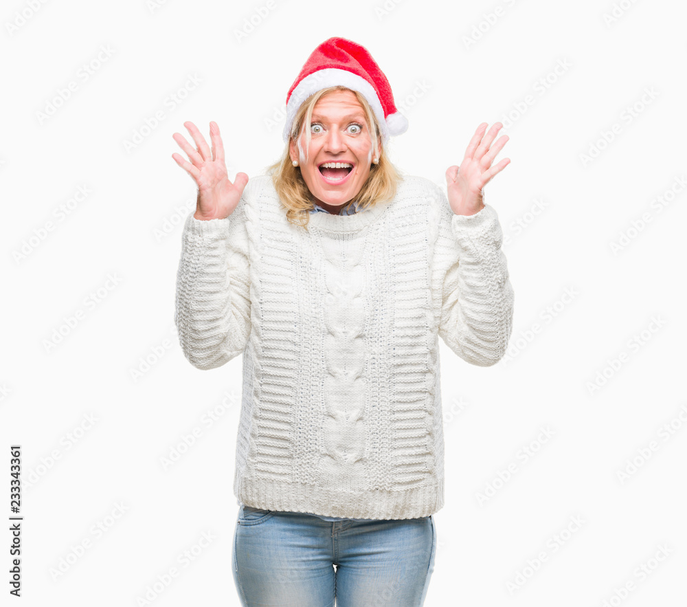 Middle age blonde woman wearing christmas hat over isolated background celebrating mad and crazy for success with arms raised and closed eyes screaming excited. Winner concept Middle age blonde woman wearing christmas hat over isolated background celebrating mad and crazy for success with arms raised and closed eyes screaming excited. Winner concept