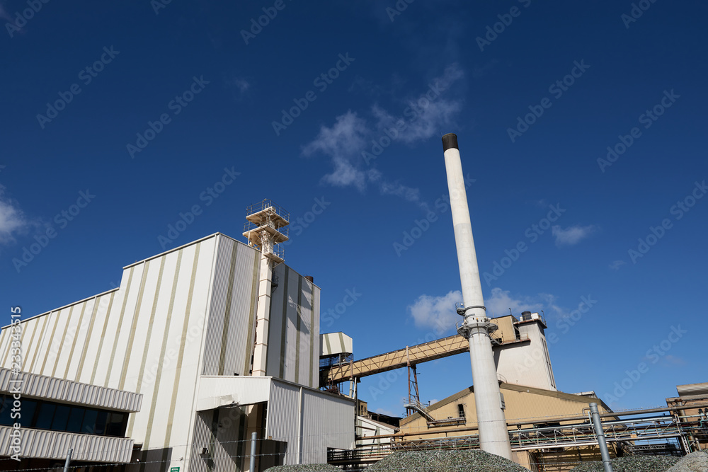Glass factory buildings with a chimney on a sunny blue sky day. Glass factory buildings with a chimney on a sunny blue sky day.