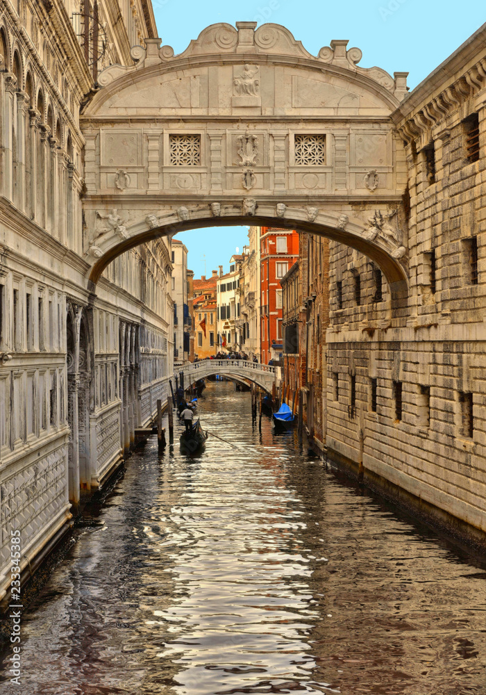 Gondola on small canal passing towards famous Bridge of Sighs (Ponte dei Sospiri) in Venice, Italy.
