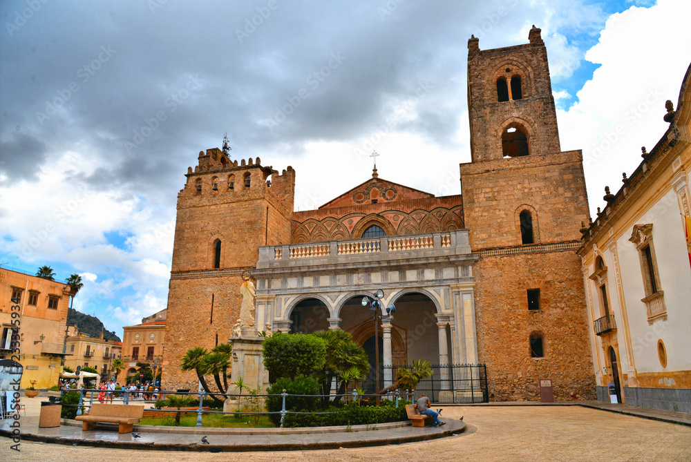 The Cathedral of Monreale, is one of the greatest examples of Norman and Arab architecture in Sicily with square with tourists and cloudy summer blue sky, Palermo, Italy