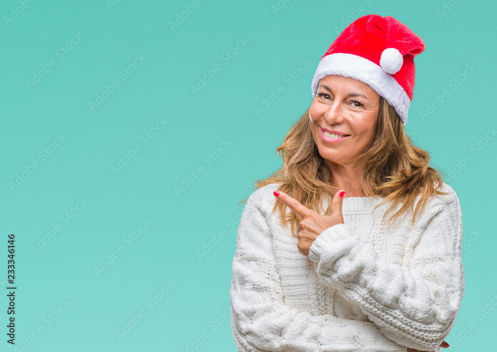 Middle age senior hispanic woman wearing christmas hat over isolated background cheerful with a smile of face pointing with hand and finger up to the side with happy and natural expression on face Middle age senior hispanic woman wearing christmas hat over isolated background cheerful with a smile of face pointing with hand and finger up to the side with happy and natural expression on face
