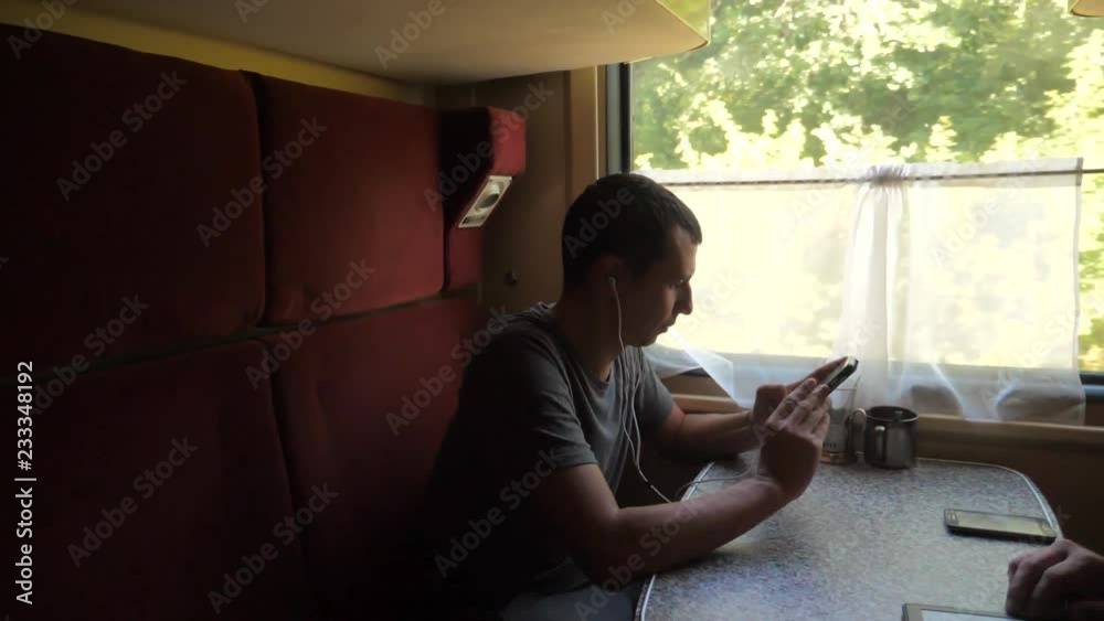 silhouette of man on a train railway car listening to music on headphones writing a message in a messenger social media smartphone. slow motion lifestyle video travel by train . man with smartphones silhouette of man on a train railway car listening to music on headphones writing a message in a messenger social media smartphone. slow motion lifestyle video travel by train . man with smartphones