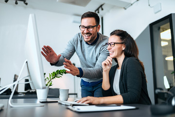 Teawork and success concept. Two business people smiling and looking at computer screen.