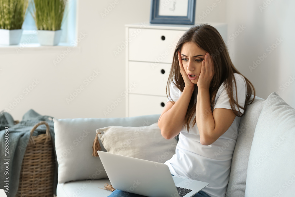 Emotional young woman after making mistake during work on laptop at home Emotional young woman after making mistake during work on laptop at home