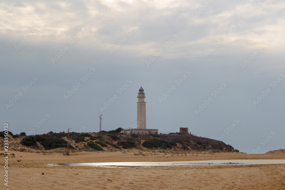 Sandy beach at Trafalgar in spain overlooking the sea the waves and the lighthouse
