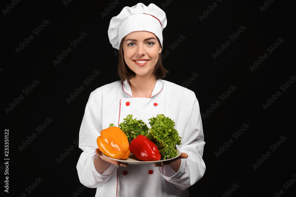 Young female chef with vegetables on dark background Young female chef with vegetables on dark background