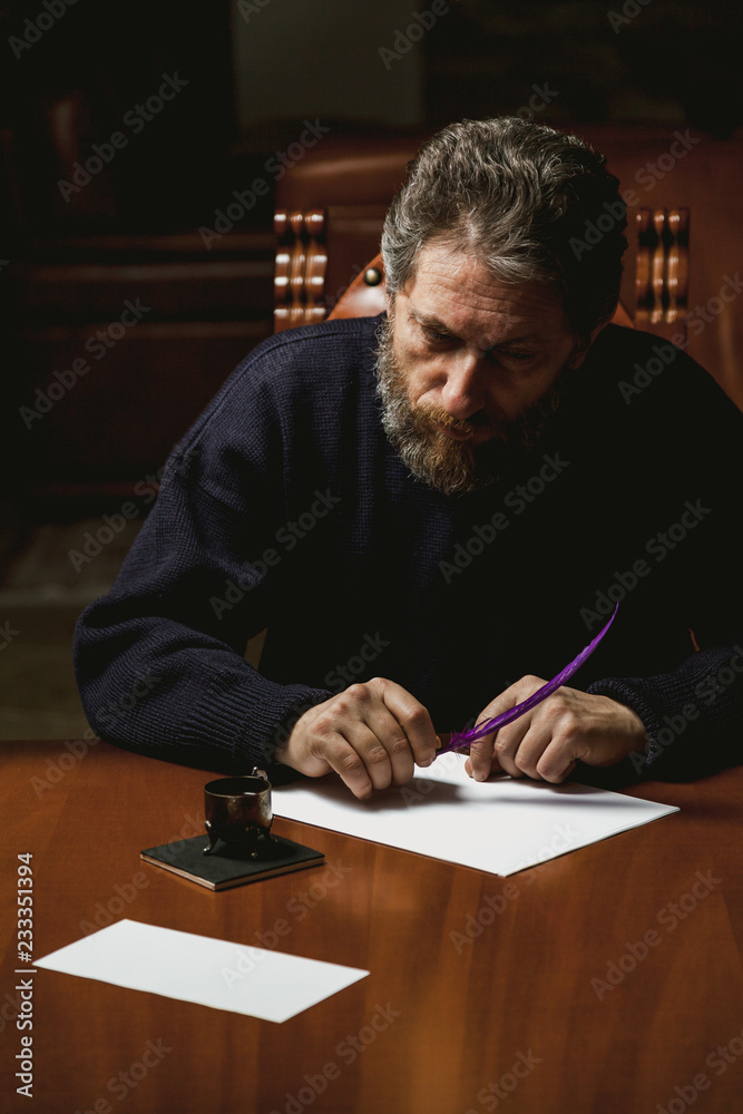 writer with beard writes on white sheet with goose feather