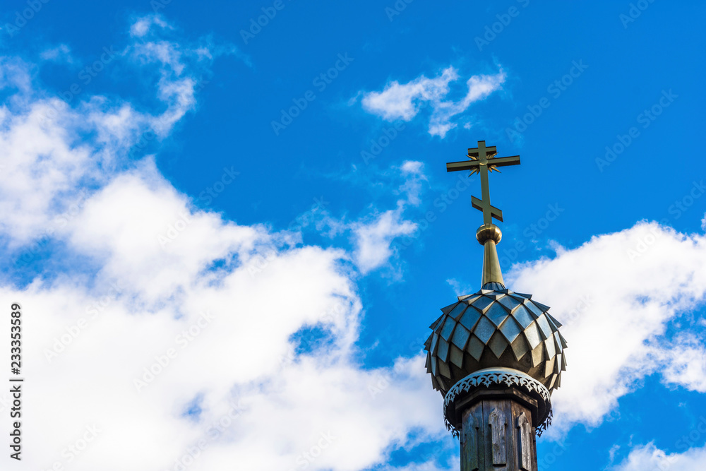 Orthodox church dome with a cross on the background of a cloudy sky.