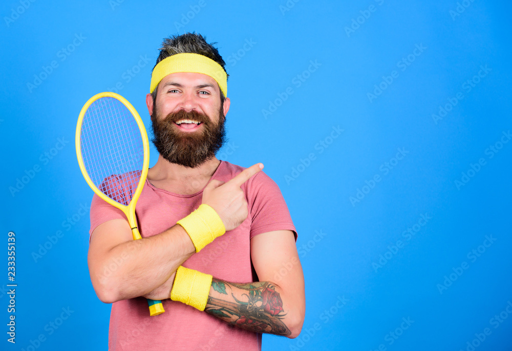 Tennis club concept. Man bearded hipster wear old school sport outfit with  bandages. Tennis player retro fashion. Athlete hold tennis racket in hand  on blue background. Tennis sport advertisement Stock Photo