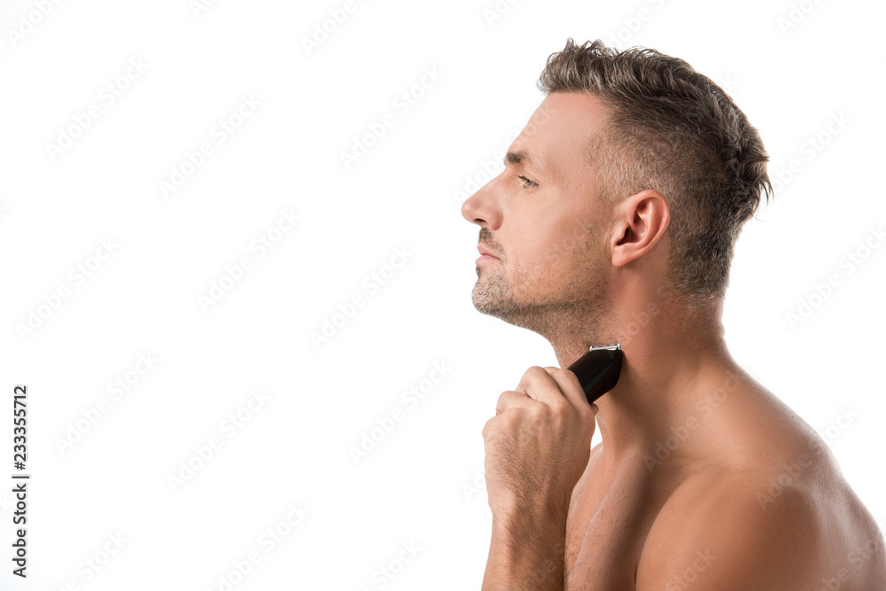 Fototapeta premium side view of handsome adult man shaving with electric trimmer isolated on white