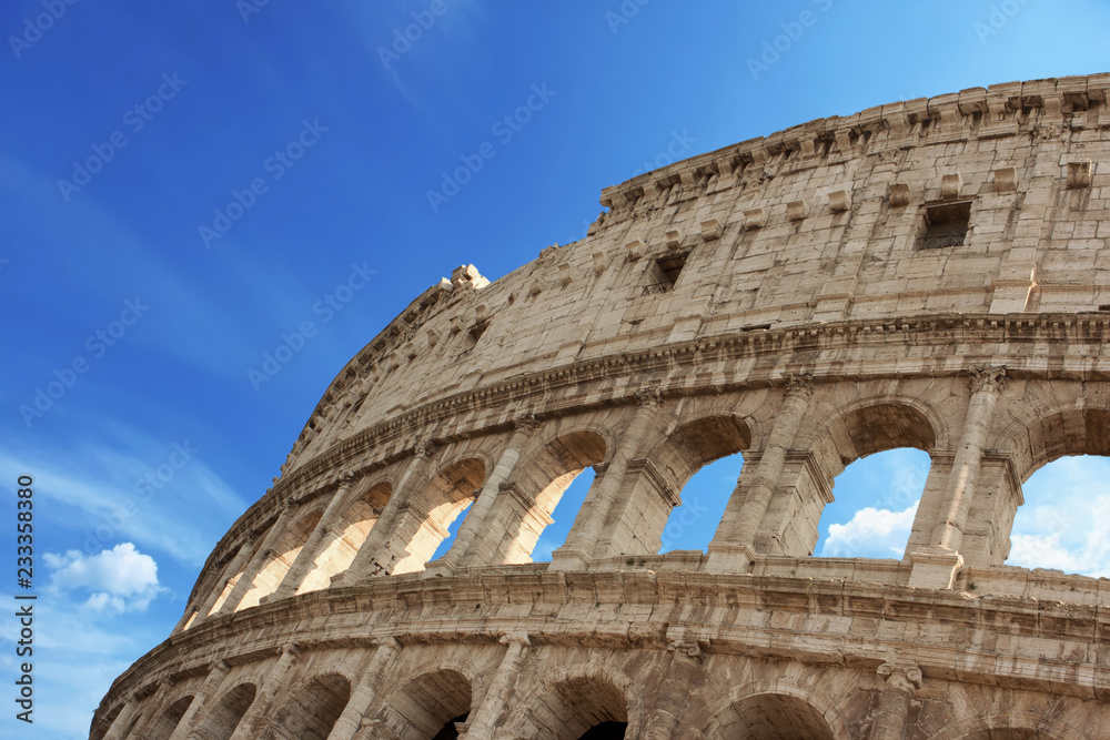 Detail of the arches of the Colosseum. Marble ruins over a blue sky, Rome, Italy