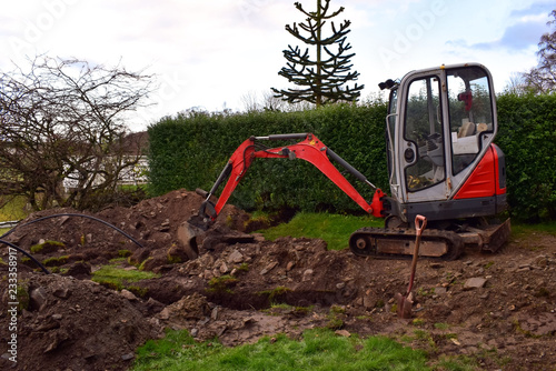 Mini Excavator dug trench in the garden. Works on laying communications.