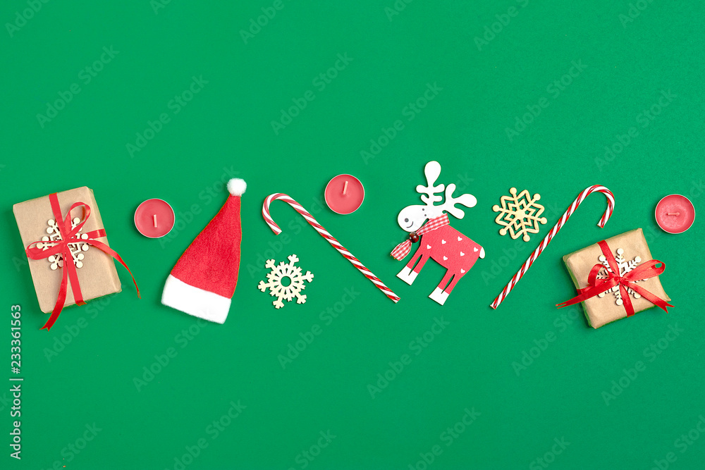Christmas composition. Christmas decoration gifts, , Santa Claus hat , candy, snowflakes on green background. Flat lay, top view
