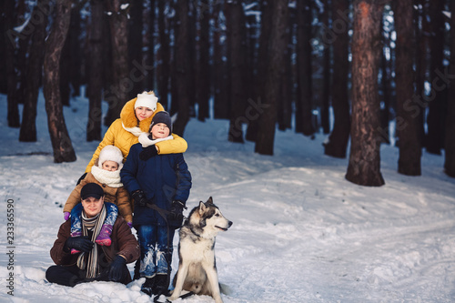 Happy european young family with big dog posing against winter pine forest