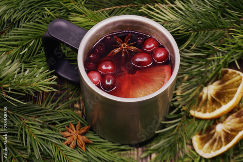 Christmas mulled wine with cranberries in metal mug Winter warming drink with spices decorated with fir branches dried oranges