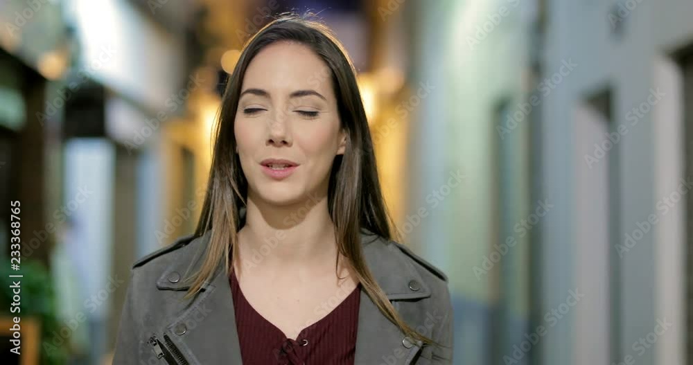Front view of a woman walking talking at camera in the night in the street