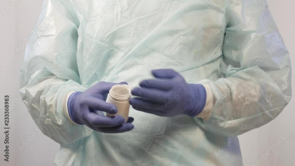 The hands of a male doctor in medical gloves remove the pills from the jar, which must be taken by the patient. The hands of a male doctor in medical gloves remove the pills from the jar, which must be taken by the patient.