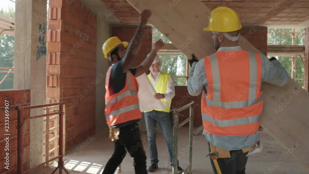 People working in construction site. Men at work in new house inside apartment building. Team of workers at work talking with engineer and looking at plans People working in construction site. Men at work in new house inside apartment building. Team of workers at work talking with engineer and looking at plans