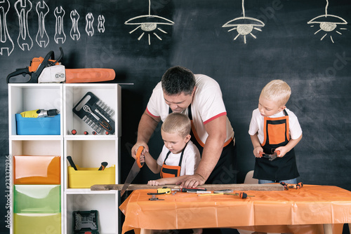 Father and two sons working in the carpentry workshop.	