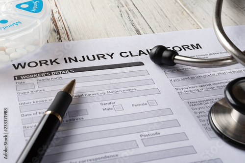 side view work injury claim form with stethoscope  and box of pills medical and insurance concept photo