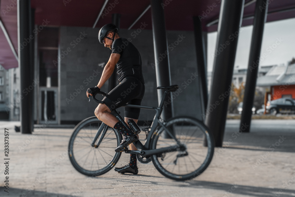 Sportsman riding bike next to modern building inside urban bridge. Sportsman riding bike next to modern building inside urban bridge.