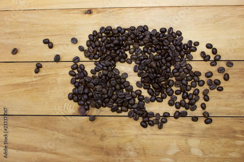 Pile of coffee bean on wooden table top view.