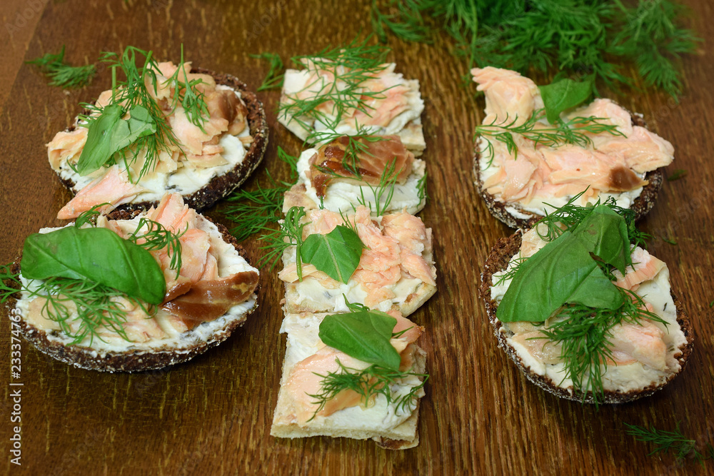 Prepared canapes with smoked salmon, cream cheese, dill and basilica toppings.