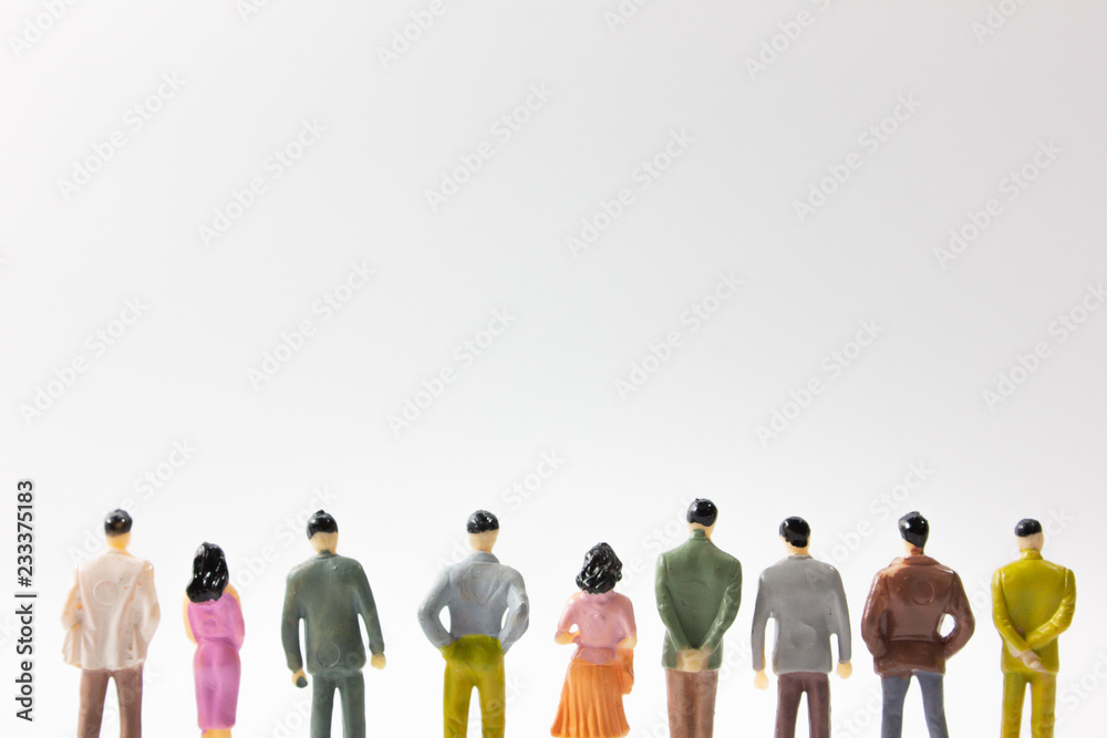 A group of miniature business people stand on white background back view cut legs. A group of miniature business people stand on white background back view cut legs.