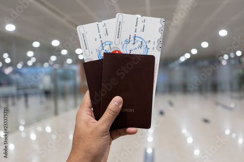 Hand holding passport and boarding pass in terminal photo