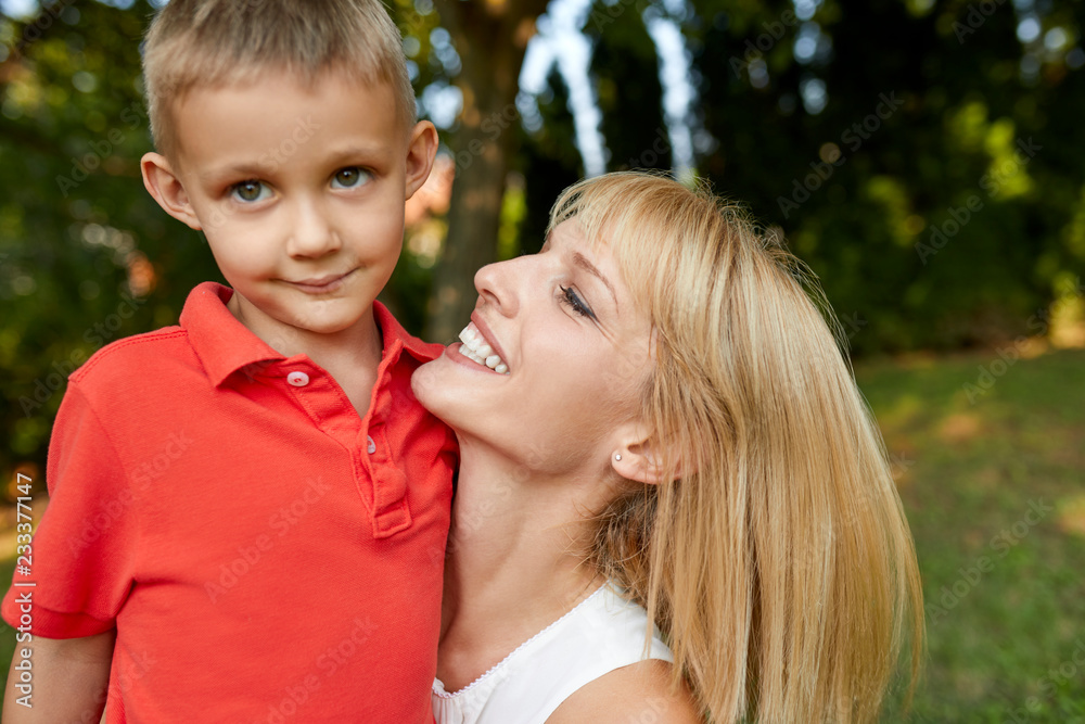 Happy mother carrying her son in garden Happy mother carrying her son in garden
