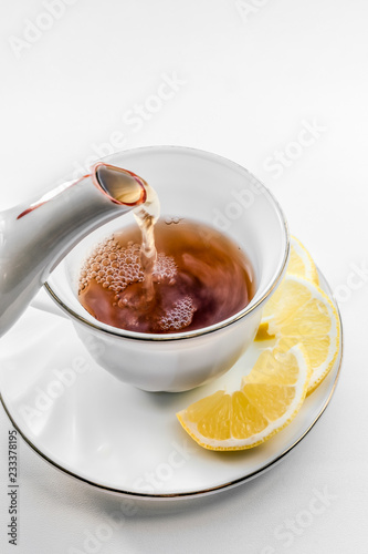 Cup of tea with lemon. Pour tea from teapot into cup.